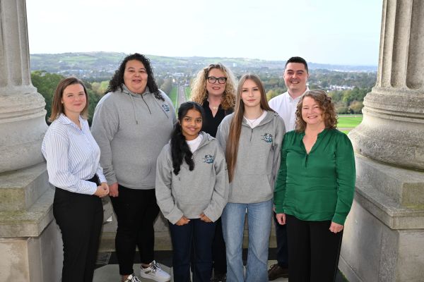 This photo shows young people from Oasis Youth who are members of Be Cyber Safe NI, it also includes their youth leader from Oasis and CiNI CEO, CiNI Head of policy and staff from NSPCC. They all stand on the balcony at Parliament Buildings Stormont. This photo was taken at the Cyber Cafe online safety event.