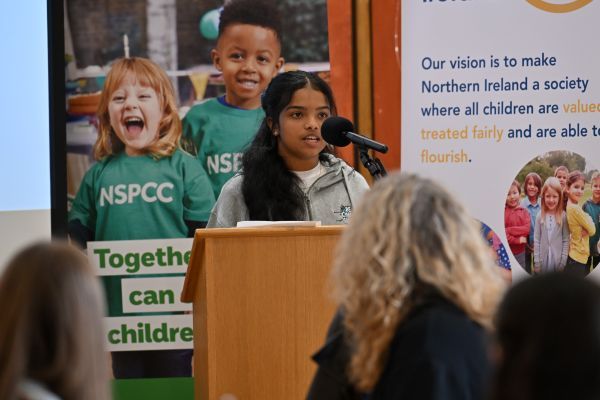 This image shows one of the young people from Be Cyber Safe NI talking from the podium during the Cyber Cafe event