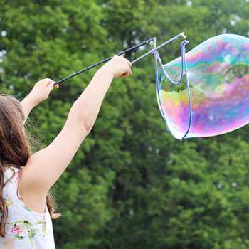 about1 a young girl in a field making a giant bubble