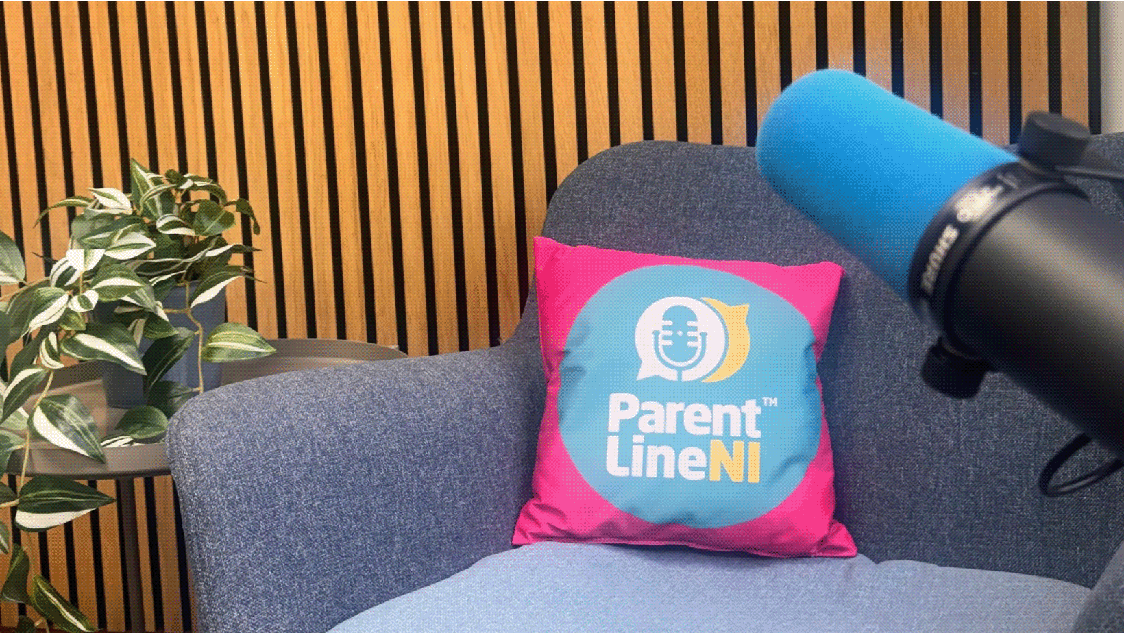 Parentline NI Podcasting Suite with a microphone, grey chair, and branded cushion from the British Podcasting Awards